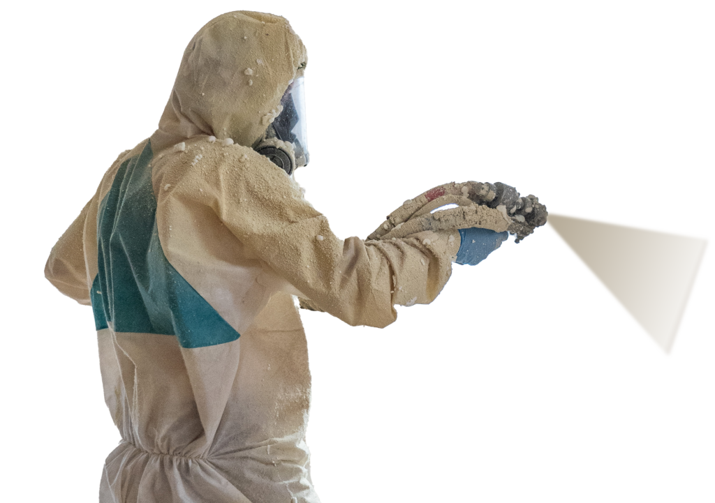 A person in a protective hazmat suit and mask is captured in side view, pointing a spray foam nozzle. Their body is covered in dusty residue, hinting at involvement in spray foam insulation work within a potentially hazardous environment.
